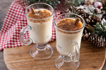 Eggnog with Cinnamon and Christmas Decorations on wooden table