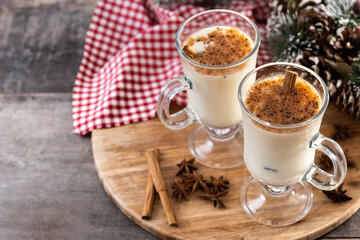 Eggnog with Cinnamon and Christmas Decorations on wooden table. Copy space