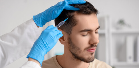 Young man receiving injection for hair growth at clinic, closeup