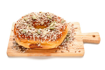Wooden board of tasty bagel with sesame and pumpkin seeds on white background