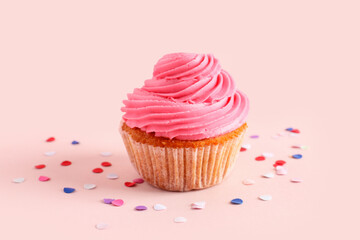 Tasty cupcake and confetti on pink background