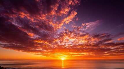 Fototapeta premium Fiery sunset painting the sky over a calm ocean with vibrant orange, red, and purple colors