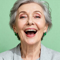 Portrait of a happy elderly woman with gray hair, smiling broadly on a green background
