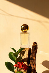 Perfume bottle with a golden lid on a warm background with a tree branch and flowers