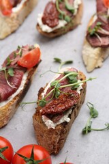 Delicious bruschettas with roast beef served on light table, closeup