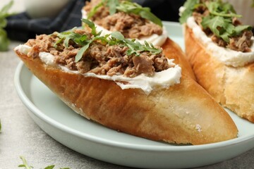 Delicious bruschettas with tuna, cream cheese and arugula on grey table, closeup