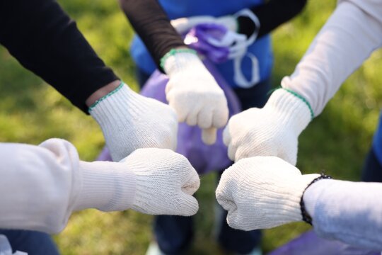 Group of volunteers bumping fists outdoors, closeup