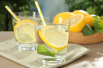 Refreshing water with lemons and mint on wooden table outdoors, closeup