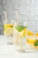 Refreshing water with lemons and mint on white marble table, closeup