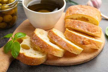 Slices of ciabatta, spices and olives on grey table, closeup
