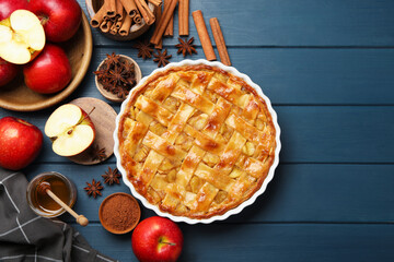 Delicious homemade apple pie in baking dish and ingredients on blue wooden table, flat lay. Space for text