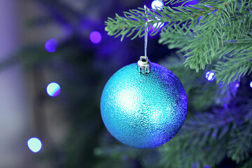 Fototapeta premium Fir tree with Christmas lights and bauble, closeup. Bokeh effect