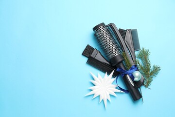 Hairdresser's tools and fir tree branches on light blue background, flat lay with space for text....