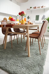 Served dining table on stylish carpet in modern kitchen