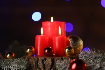Burning candles and Christmas decor on table against dark background with blurred lights, closeup. Bokeh effect
