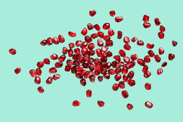 Flying fresh pomegranate seeds on turquoise background