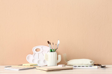 Holder with painter's supplies on light wooden desk