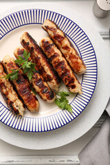 Plate of tasty grilled sausages on white wooden background
