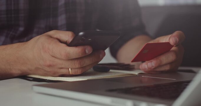 Man holding phone and red card making mobile transaction, concept of e-commerce and online finance.