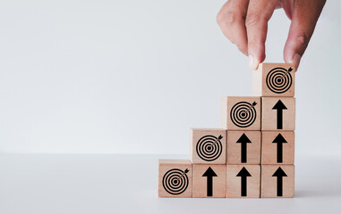 Business growth and success,setting goal and achievement concept., Hand stacking wooden blocks as stairs with target goal and upward arrow icons.,White background with copyspace.
