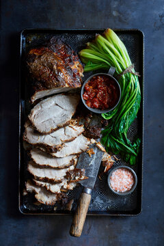 Virginia pork roast with sliced meat, tomato relish, leafy greens, and pink salt overhead