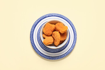 Bowl with tasty nuggets on yellow background