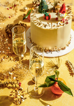 Modern Christmas Cake with Champagne on Yellow Background, golden decor on a modern yellow background