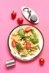 Plate with tasty pasta primavera on pink background