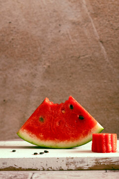 a slice of fresh organic watermeloon biten on the top placed on a wooden board with seeds