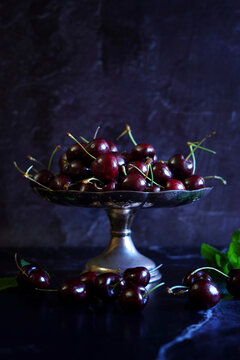 Black Cherries in Vintage Bowl Against a Dark Background.