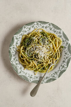 Plate of spaghetti with pesto. The surface is enhanced with a generous sprinkling of Parmigiano Reggiano, golden crouton crumbs.