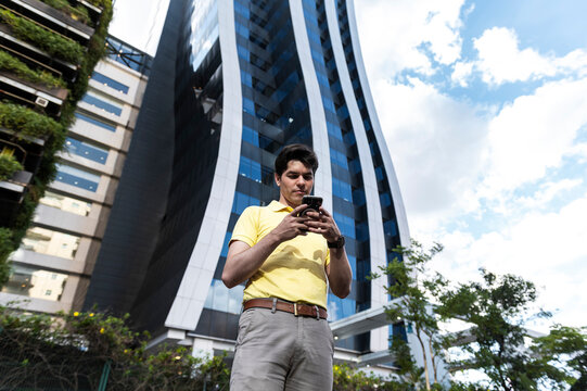 Focused professional checking phone outside innovative glass building