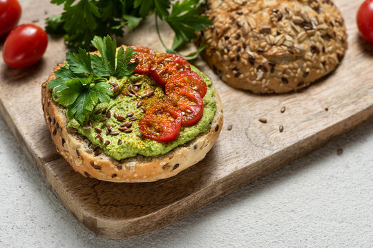 Plant-based sandwich with green spread, cherry tomatoes and flax seeds