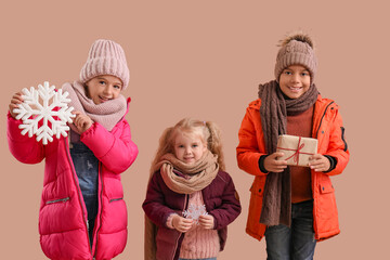 Cute children in winter clothes on beige background