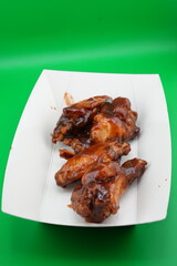 Crispy Grilled Chicken Wings on White Plate – Fast Food Photo on Green Background