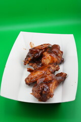Crispy Grilled Chicken Wings on White Plate – Fast Food Photo on Green Background