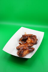 Crispy Grilled Chicken Wings on White Plate – Fast Food Photo on Green Background