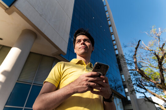 Focused businessman checking smartphone with modern architecture background