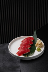 Nigiri with tuna on a white plate on a black background isolated for menu
