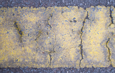 Close-up of yellow cracked asphalt. Abstract background and texture for design.