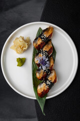 Nigiri with eel on a white plate on a black background isolated for menu