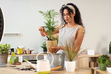 Female African-American gardener putting soil into plant pot at home