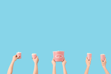 Hands holding buckets with popcorn on blue background