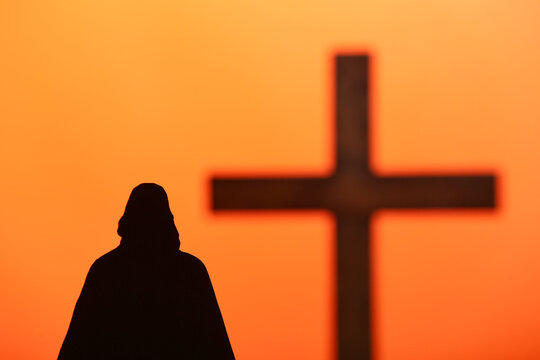 Jesus with wooden cross on orange background. Good Friday concept