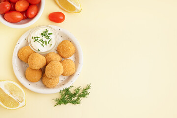 Plate with delicious fried mozzarella balls, sour cream and tomatoes on beige background