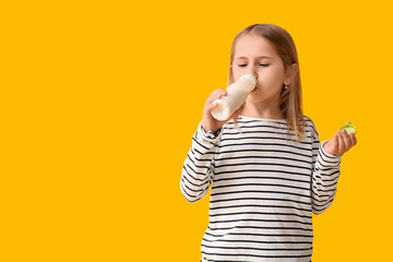 Cute little girl drinking yogurt on yellow background