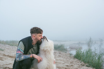 man playing with his cute samoyed dog at the lake during sunset