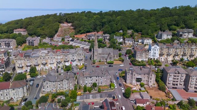 Aerial drone circle shot of the historic Holy Trinity Church and residential neighborhood in Weston-super-Mare, Somerset, England, UK on a bright summer day.