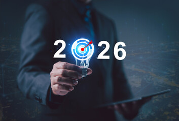 Businessman holding light bulb with 2026 target symbol, representing business goal, innovation,...