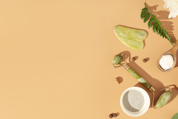 Face massage tools and natural ingredients for cosmetic mask on beige background